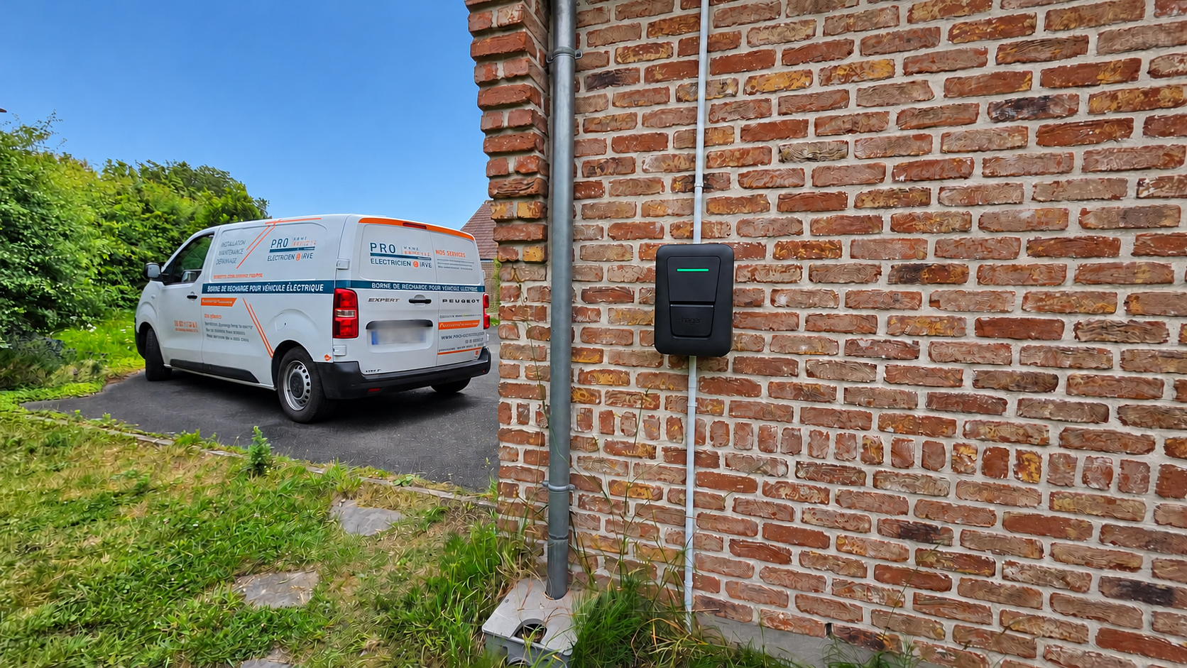 Borne Hager Witty One sur un mur en briques à Esquelbecq, avec le fourgon Pro Home Services à proximité